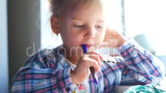 可爱的小女孩坐在她的桌子上用蜡笔画画视频的预览图