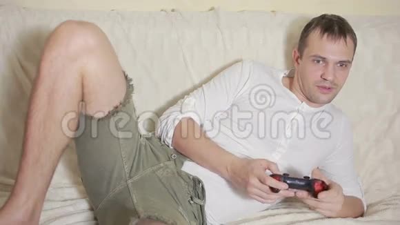 坐在沙发上的男人在黑暗的房间里玩电子游戏视频的预览图