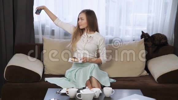 漂亮的年轻女人坐在咖啡馆里吃蛋糕用触摸板喝茶微笑视频的预览图
