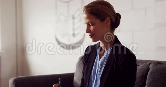 严肃的女商人坐在沙发上写笔记视频的预览图