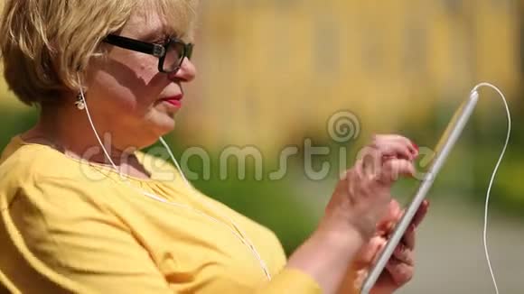 穿黄色夹克的女人用平板电脑女士手持耳机视频的预览图