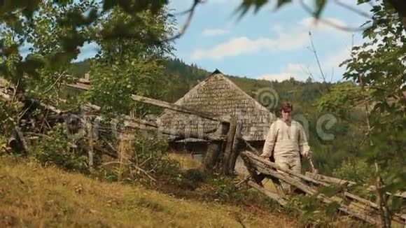 穿着传统乌克兰服装的年轻樵夫拿着斧头光着脚去森林视频的预览图