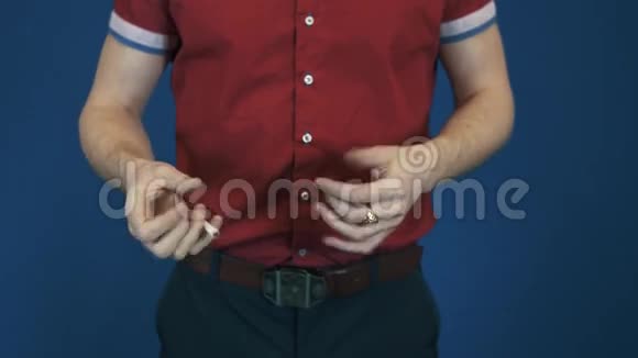 合拢魔术师穿红色衬衫表演魔术消失在手中香烟视频的预览图