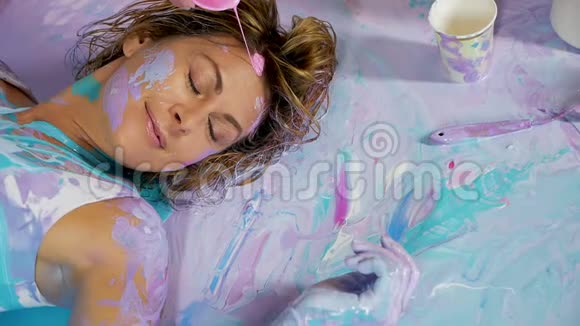 涂了颜料的瑜伽女孩躺在画背上视频的预览图