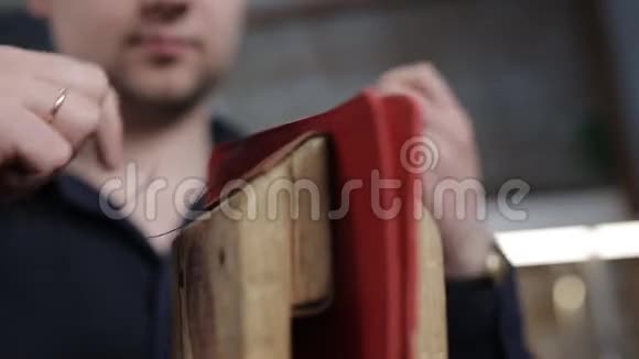 男人用自己的手在皮革车间里用一根针来制作一个棕色的皮夹特写视频的预览图