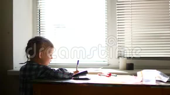 可爱的小女孩坐在她的桌子上用蜡笔画画视频的预览图