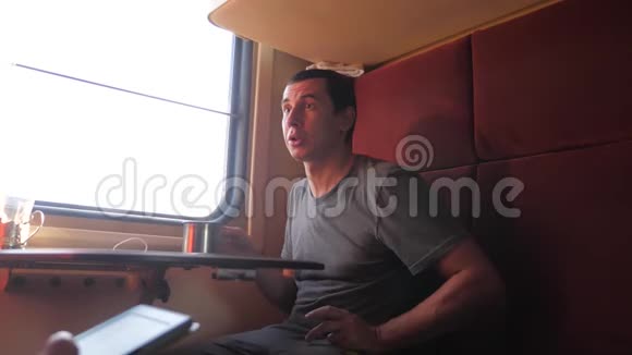 男人坐在火车车厢里捧着咖啡喝茶慢动作视频男人视频的预览图