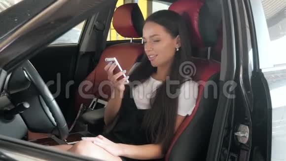 漂亮的女商人一边发短信一边坐在带红色椅子的商务车厢里年轻的学生女孩视频的预览图