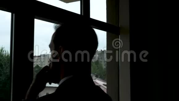一位剪影的商人透过办公室的窗户视频的预览图