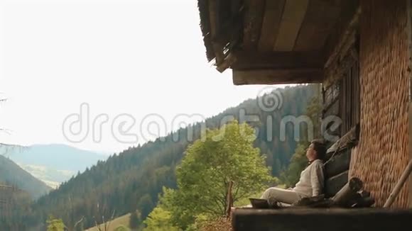喀尔巴阡山上的一个年轻的喀尔巴阡山乡下人坐在山上的避难所边缘视频的预览图