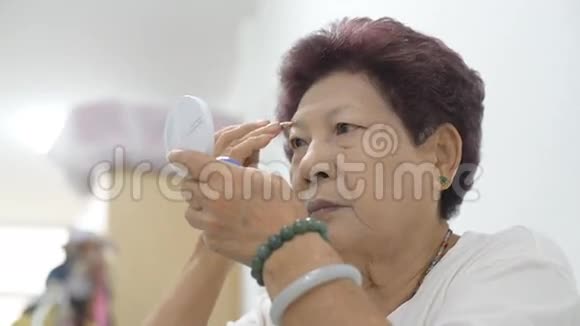 老妇人看着镜子正在化妆视频的预览图