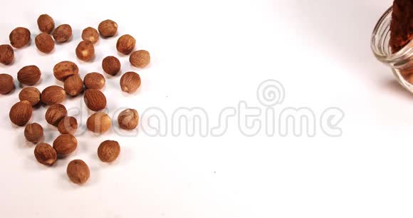 肉豆蔻肉豆蔻粉白色背景下落在肉豆蔻粉上的坚果慢动作视频的预览图