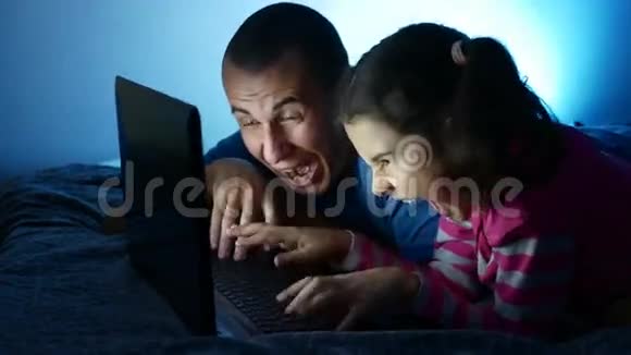 十几岁的女孩和男人爸爸和女儿惊讶地哭着在笔记本电脑上工作在网上玩网络娱乐游戏视频的预览图