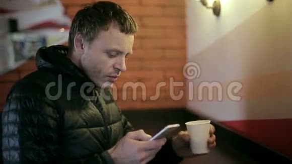 男人喝咖啡和使用智能手机视频的预览图
