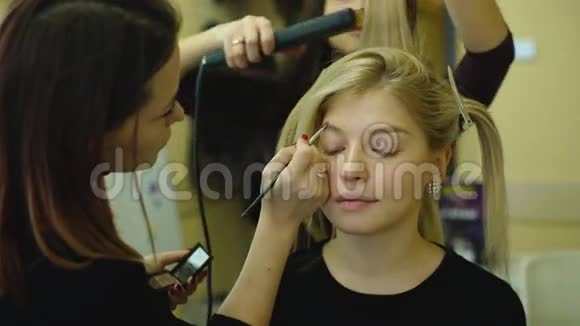 化妆的过程化妆师在模特脸上用刷子工作年轻金发美女的画像视频的预览图