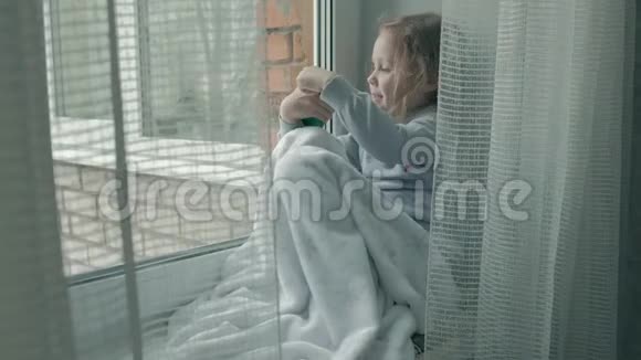 幸福的小女孩留着红色波浪发坐在窗台上盖着毯子用电话聊天视频视频的预览图