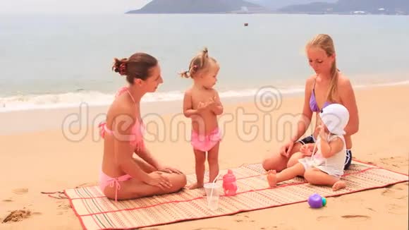 两个母亲的小女儿坐在垫子上玩耍视频的预览图