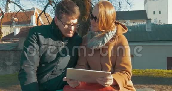 男人和女人在平板电脑上看视频视频的预览图