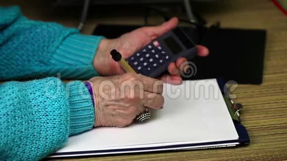 老妇人写字并使用计算器视频的预览图