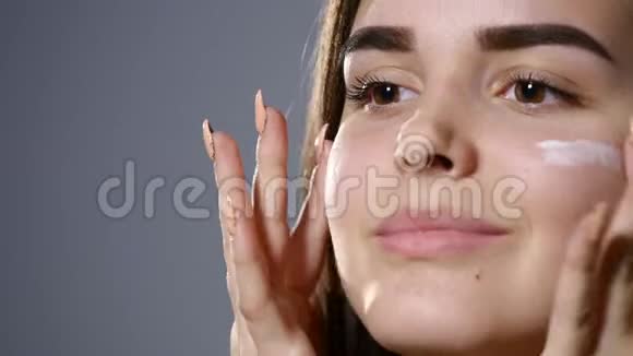 年轻漂亮的女人脸上涂着奶油灰蒙蒙的视频的预览图