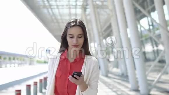 穿红衬衫的女人拿着手提箱在电话里说话视频的预览图