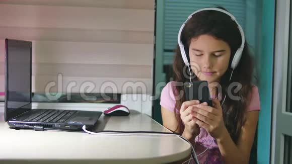 带着耳机坐着玩智能手机的少女在智能手机网络上玩网络游戏的女生视频的预览图