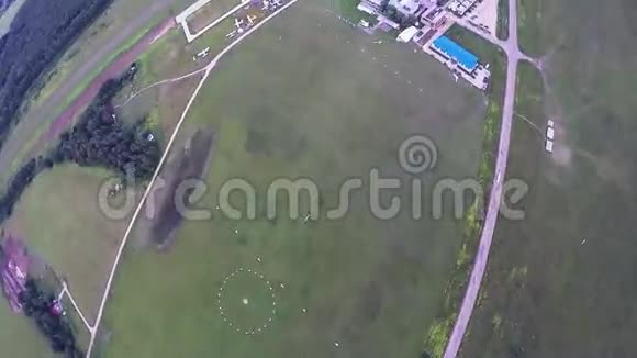 专业跳伞员乘降落伞飞下绿野森林景观视频的预览图