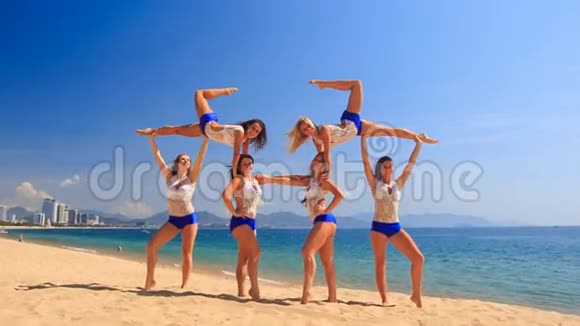 穿白色蓝色服装的啦啦队员瑞典人在海滩上跌倒视频的预览图