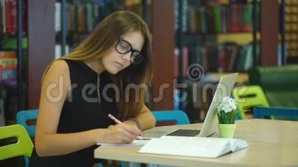在城市图书馆的笔记本电脑上工作的严肃的女学生视频的预览图
