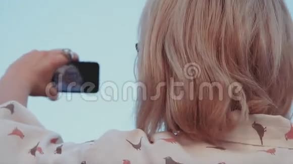 年轻的美女带着智能手机自拍视频的预览图