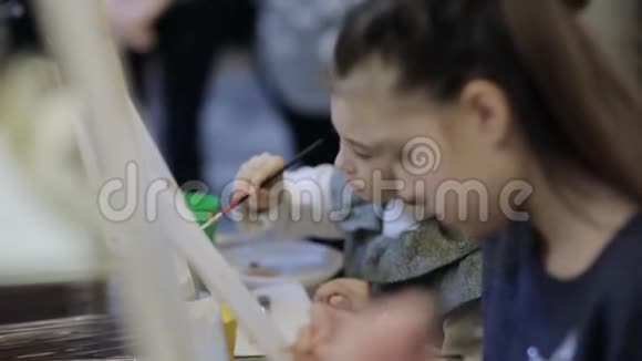 艺术学校一群带画架的孩子用画笔和颜料作画视频的预览图