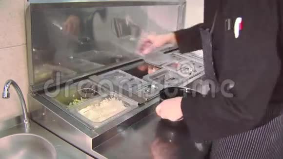 厨师从桌子上的小容器中取出切好的绿色植物大米放在小锅里餐厅视频的预览图