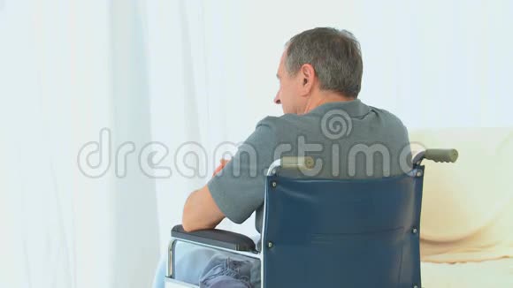 一个坐在轮椅上的人透过窗户看着视频的预览图