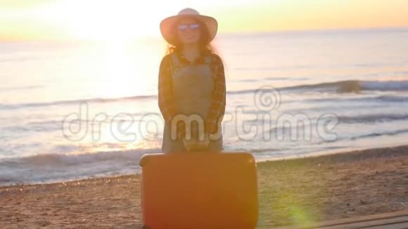 日落时带着手提箱的年轻女旅行者视频的预览图