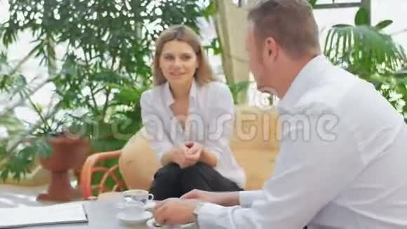 两个商人和商人坐在咖啡馆里讨论工作时刻视频的预览图