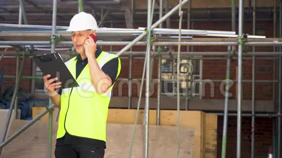 男建筑工领班建筑工人在建筑工地用手机交谈视频的预览图