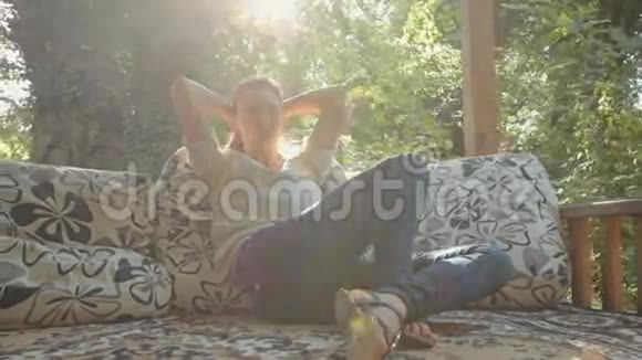 迷人的女人在森林里的露台上放松和坐在枕头上视频的预览图