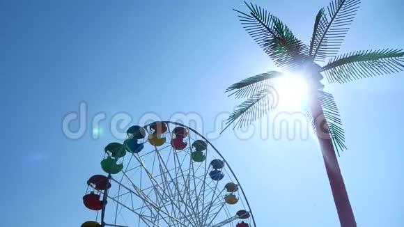 游乐园摩天轮越过蓝天游乐园和棕榈视频的预览图