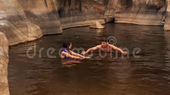 男的向女孩展示在山溪创造的湖里游泳视频的预览图
