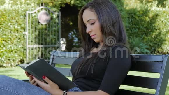 可爱的黑发女人带着书在户外摆姿势视频的预览图