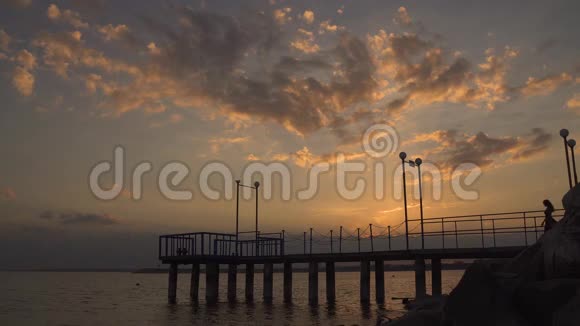 日落时分在码头上散步的美丽女孩的剪影视频的预览图