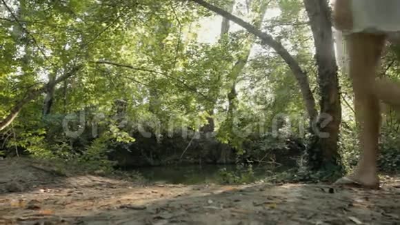 美丽的金发碧眼穿着一件衣服在森林里的池塘边休息视频的预览图