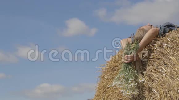 女孩躺在稻草堆上捧着一束白色的雏菊视频的预览图