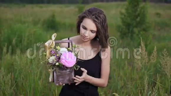 新鲜的花放在时尚的抽屉里晚上美丽的黑发女郎在一片花圃里视频的预览图