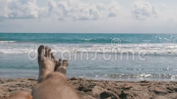 躺在海边的沙滩上的男人的腿视频的预览图