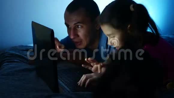 十几岁的女孩和男人爸爸和女儿在笔记本电脑上工作在网上玩娱乐游戏视频的预览图
