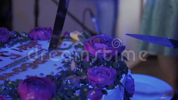 在庆祝活动中女人用刀切了巨大的玫瑰蛋糕紫色照明视频的预览图