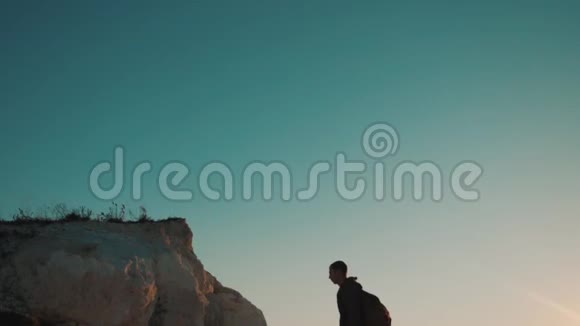 一位游客在日落探险时爬上山顶的剪影生活方式的剪影视频的预览图