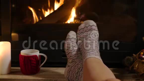 女人坐在壁炉旁端着一杯热饮和一本书视频的预览图