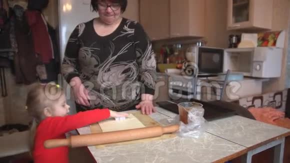 祖母带着孙子和孙女在厨房的桌子上做饼干视频的预览图